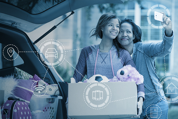 600x400_DuotoneImages_Utilitarians2 Teenage daughter smiling and carrying a box of toys while mother takes a selfie of them both